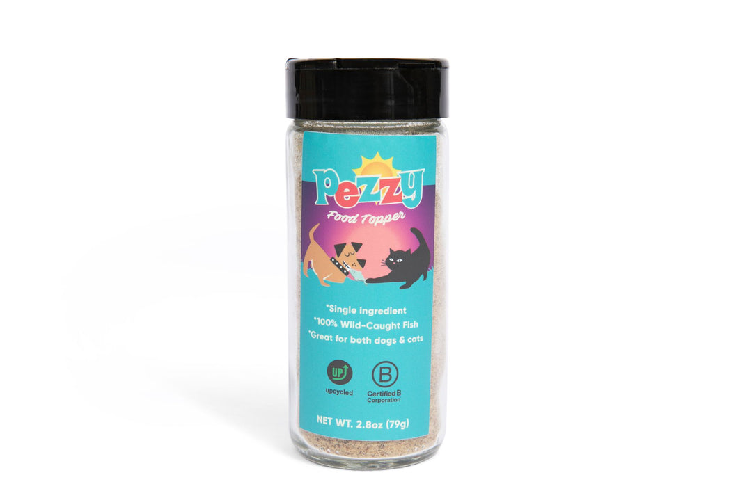 Glass of Pezzy Pets food topper, 2.8oz net weight. Front of packaging with Pezzy logo of dog and cat fighting over a fish with product attributes of single ingredient, 100% wild-caught fish and great for both dogs & cats.